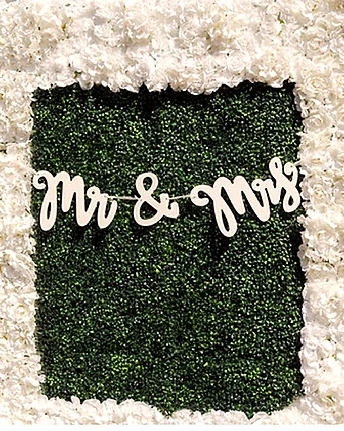 Mr and Mrs sign on a greenery and white rose flower wall